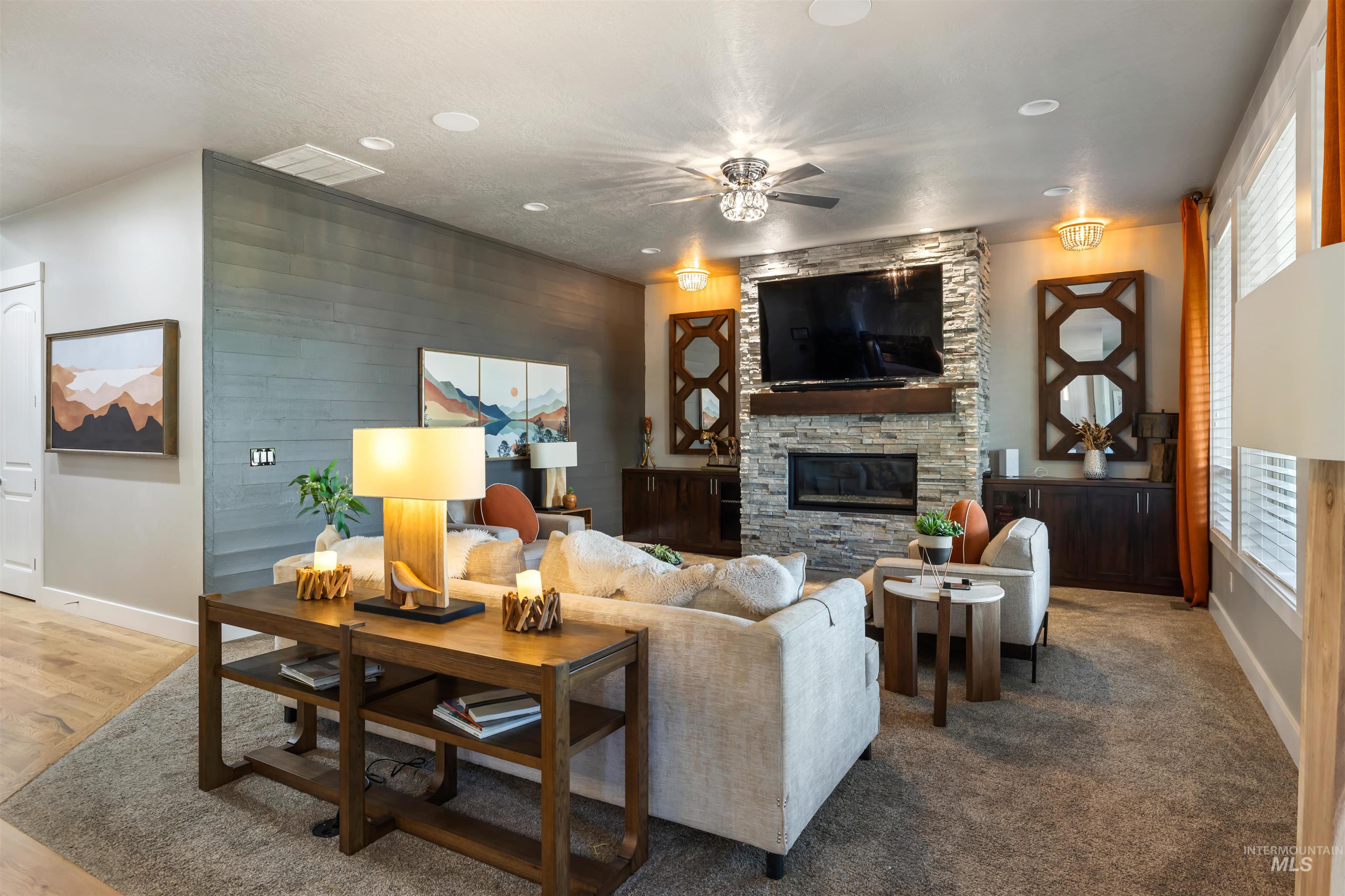 Living room featuring a stone fireplace and a ceiling fan