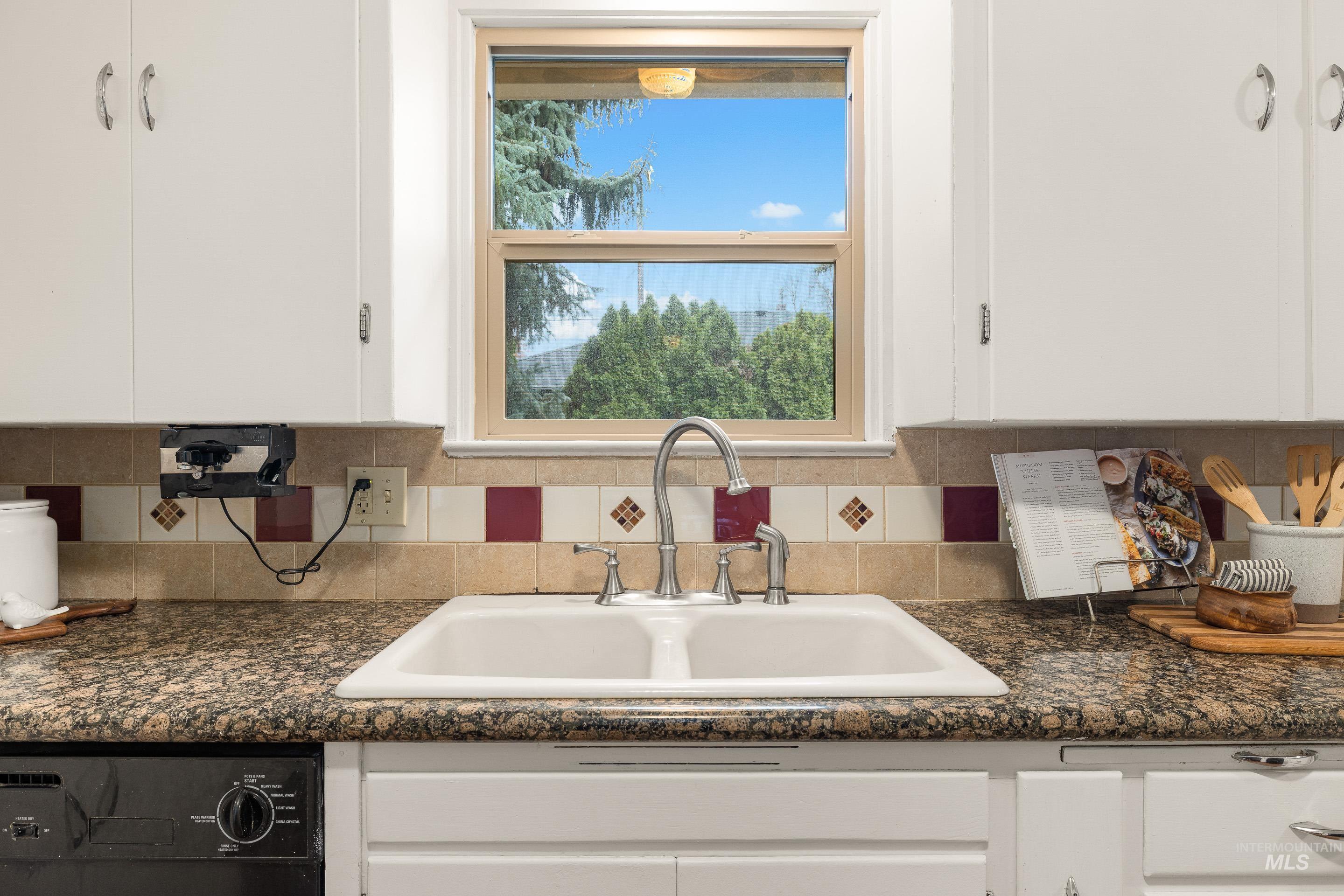 Kitchen featuring white cabinetry, dark stone countertops, decorative backsplash, and dishwasher