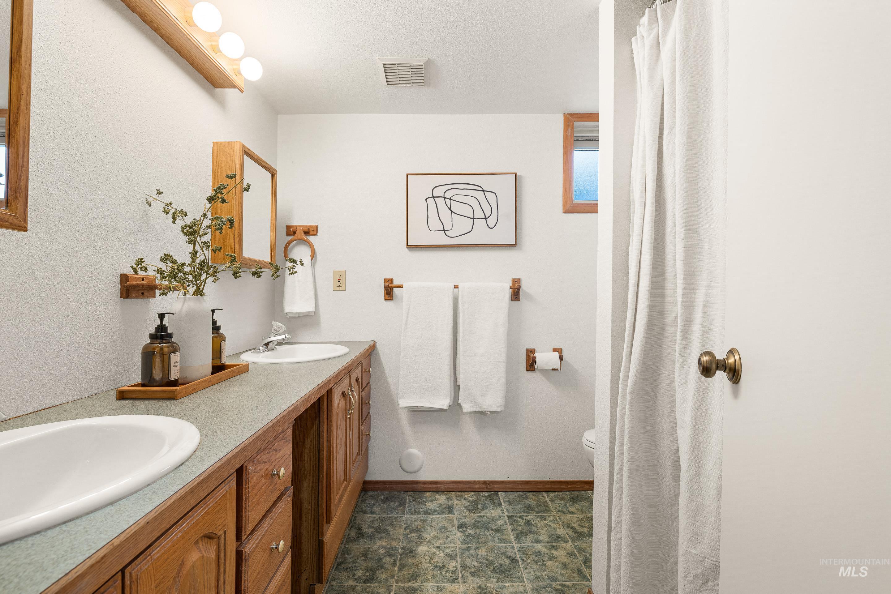 Bathroom featuring double vanity and curtained shower