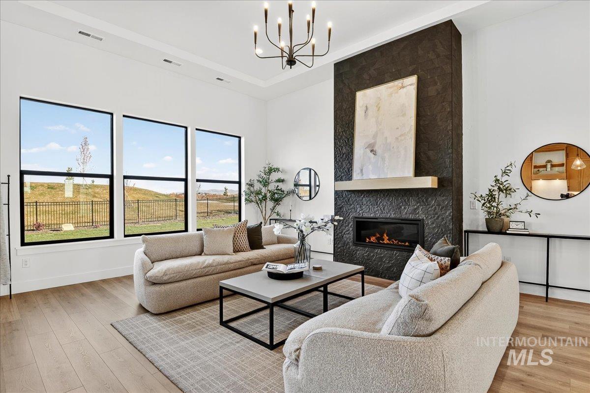 Living room with a fireplace, light wood finished floors, and a chandelier