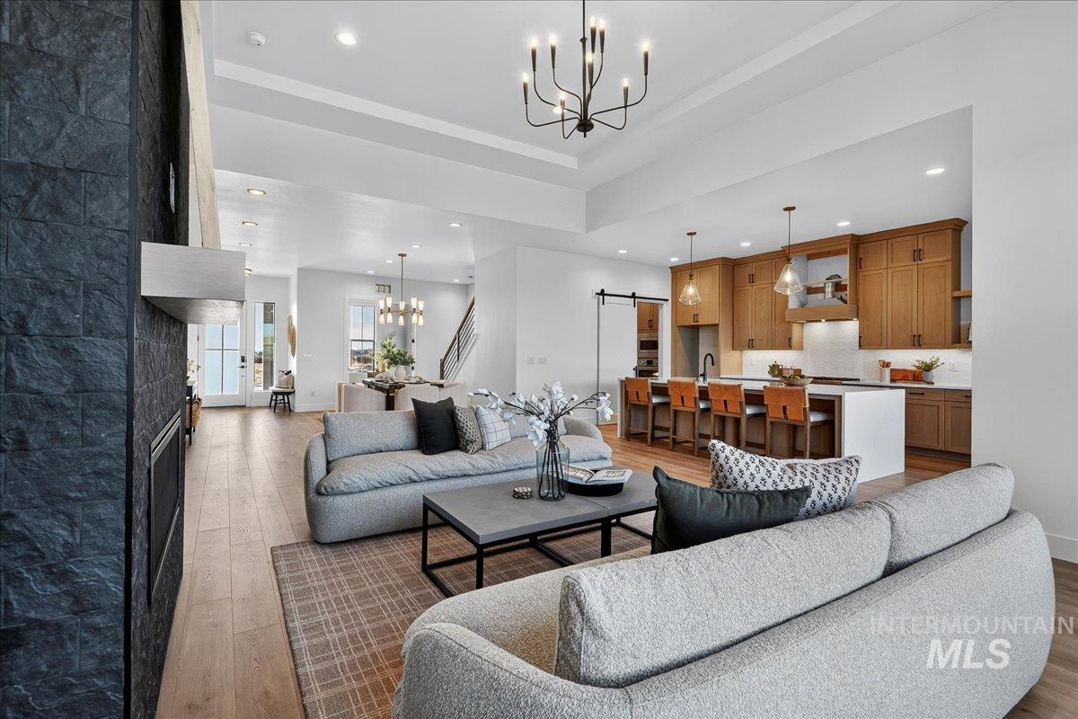 Living area featuring a chandelier, a barn door, recessed lighting, light wood-style flooring, and a raised ceiling