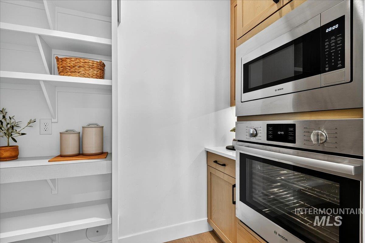 Kitchen with stainless steel appliances, light brown cabinets, and light wood-style floors