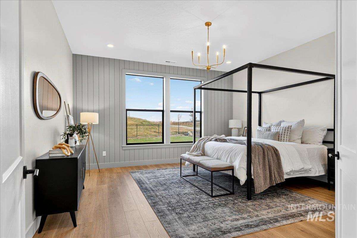 Bedroom featuring light wood-type flooring, recessed lighting, a chandelier, and wood walls