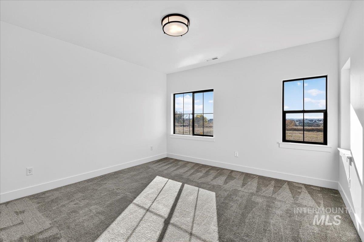 Carpeted spare room featuring baseboards