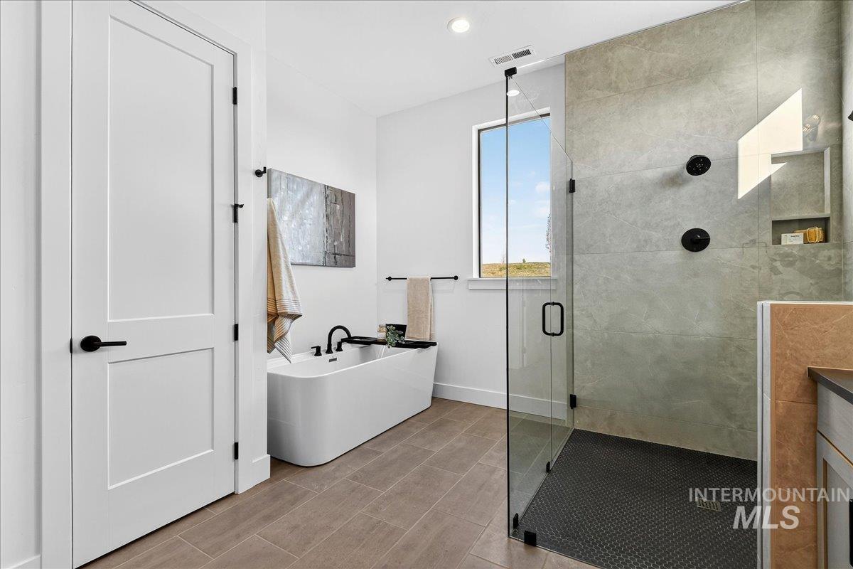 Bathroom with a stall shower, a soaking tub, and recessed lighting