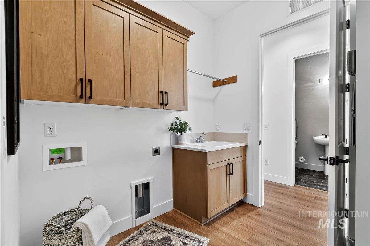Washroom featuring cabinet space, light wood-type flooring, hookup for a washing machine, and hookup for an electric dryer
