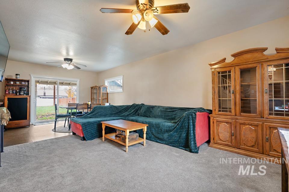 Living area with light colored carpet and a ceiling fan