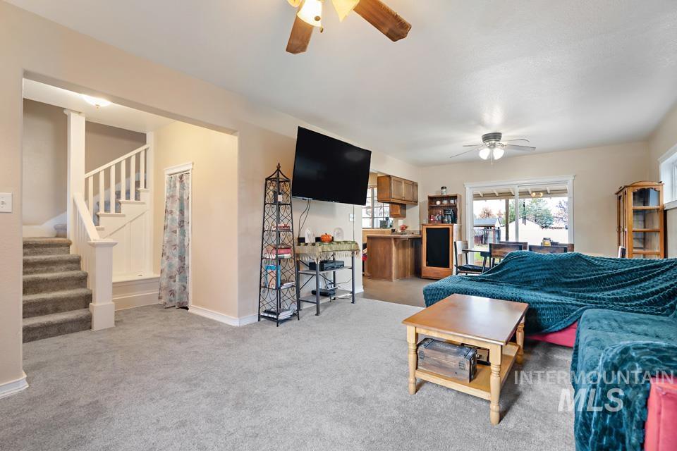 Living area featuring stairway, ceiling fan, and carpet floors