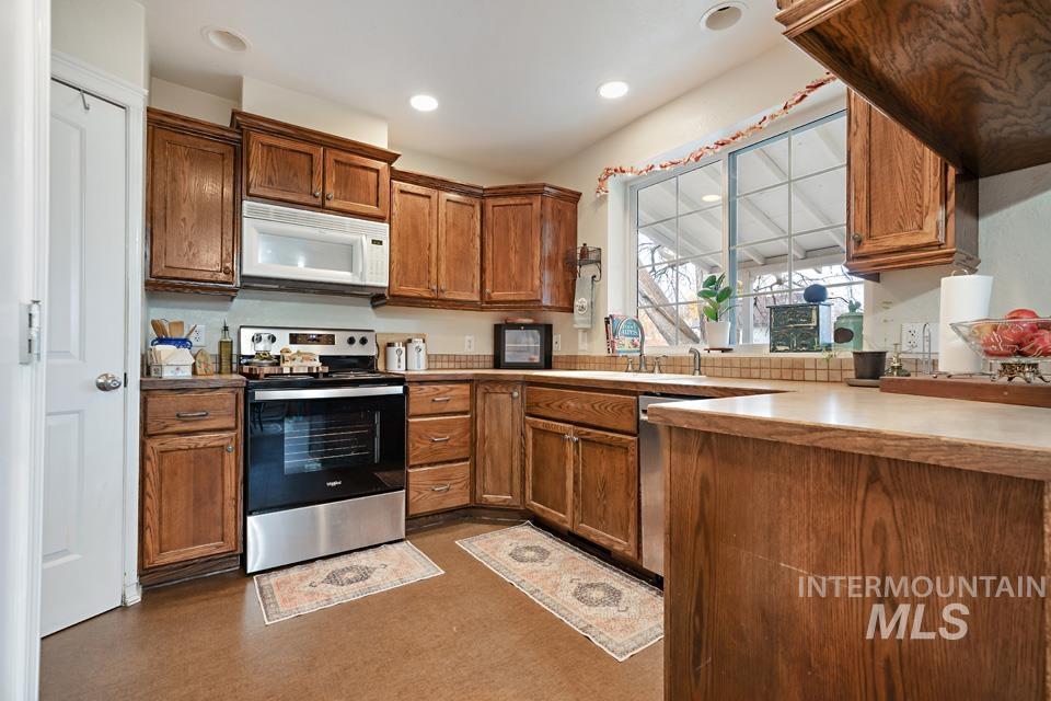 Kitchen with stainless steel appliances, brown cabinetry, recessed lighting, and light countertops