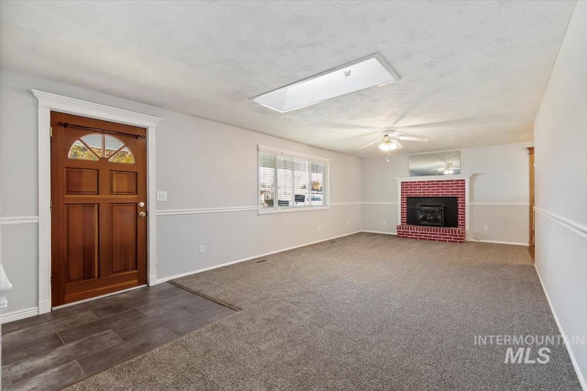 Foyer entrance with a skylight, carpet flooring, a brick fireplace, and a ceiling fan