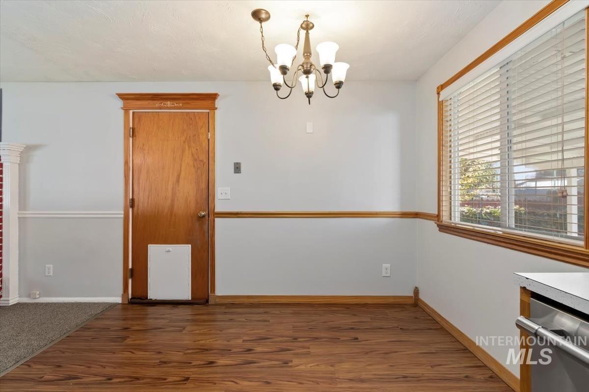 Unfurnished dining area with a chandelier and wood finished floors