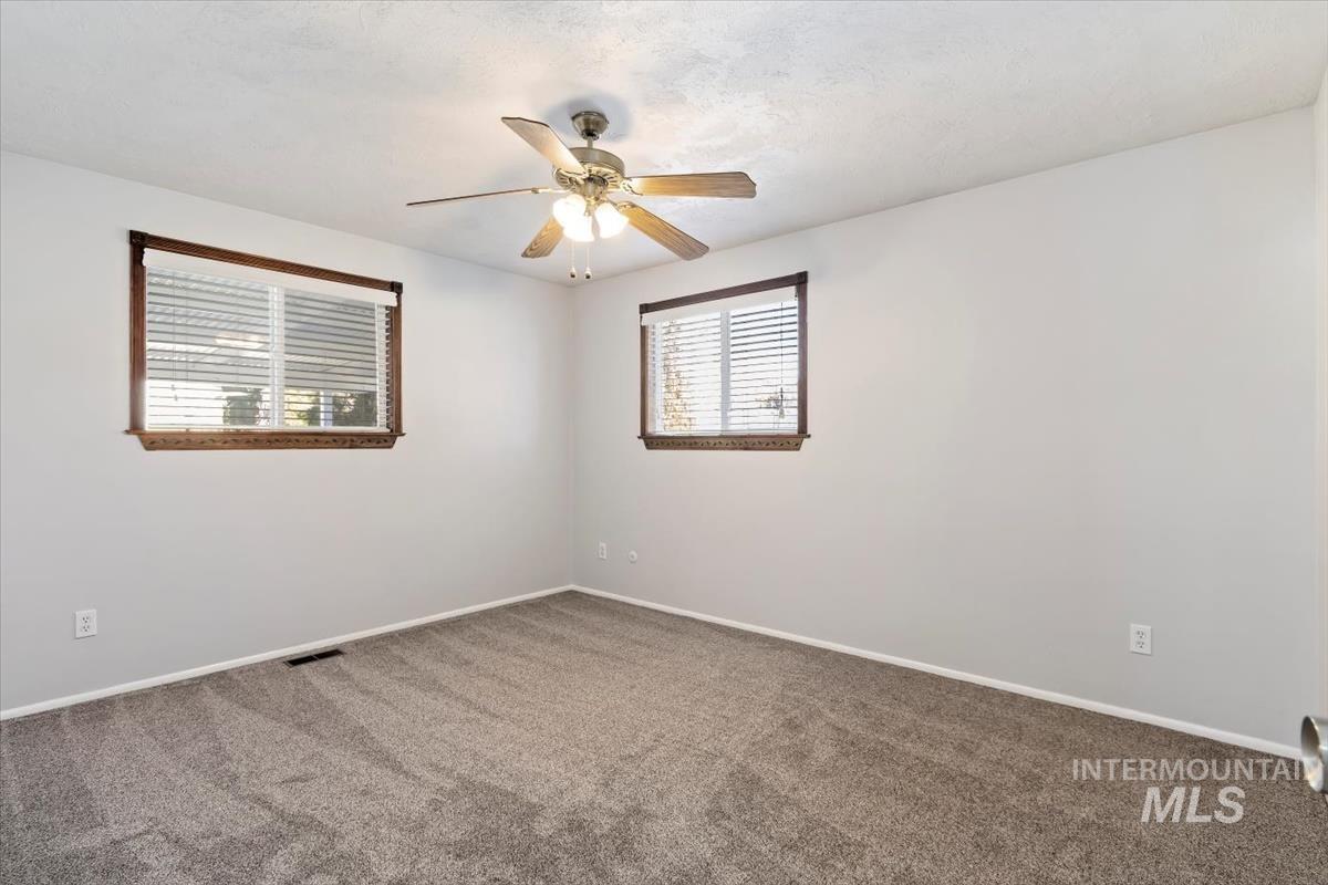 Carpeted spare room with baseboards and ceiling fan