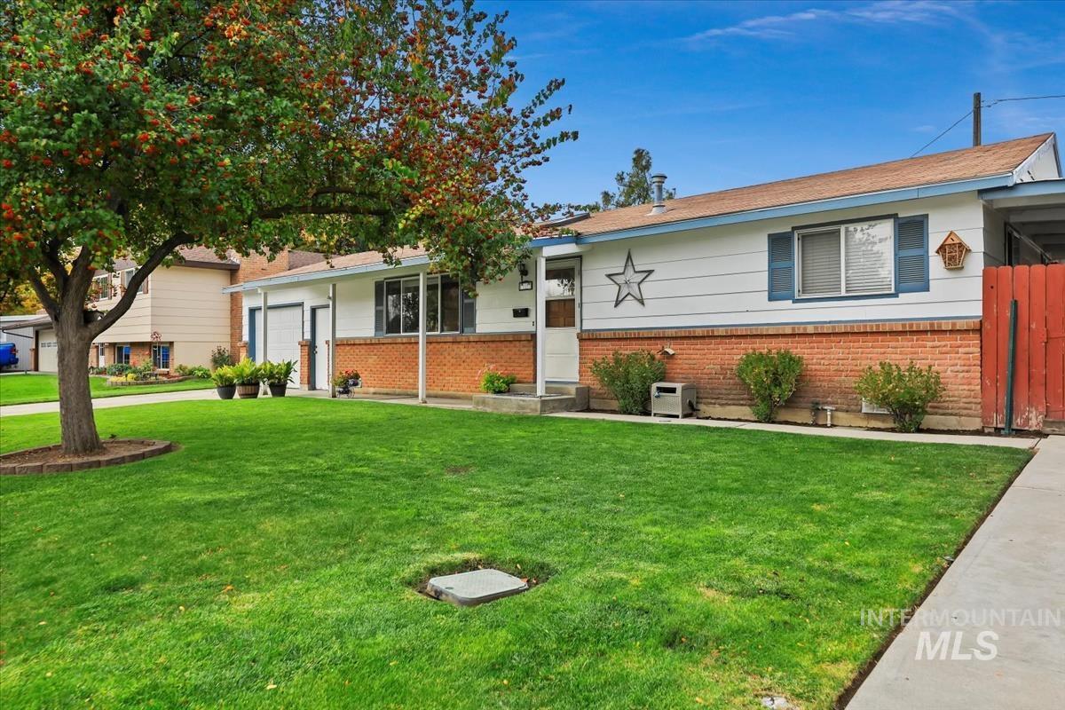 View of front facade with brick siding, a front lawn, and a garage