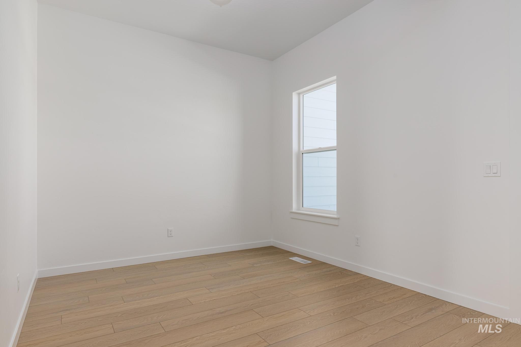 Spare room featuring light wood-type flooring and baseboards