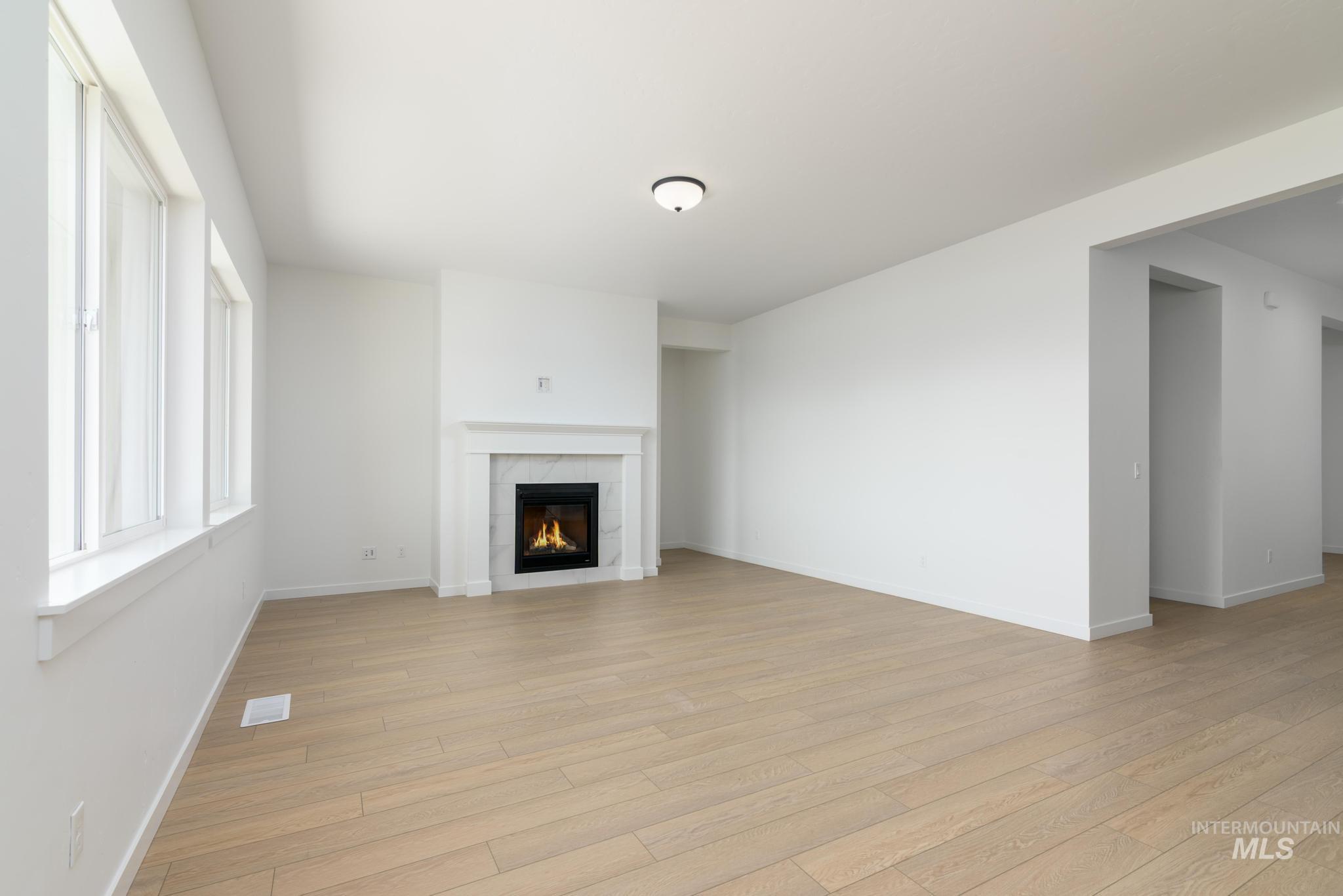 Unfurnished living room featuring light wood-style flooring and a tiled fireplace