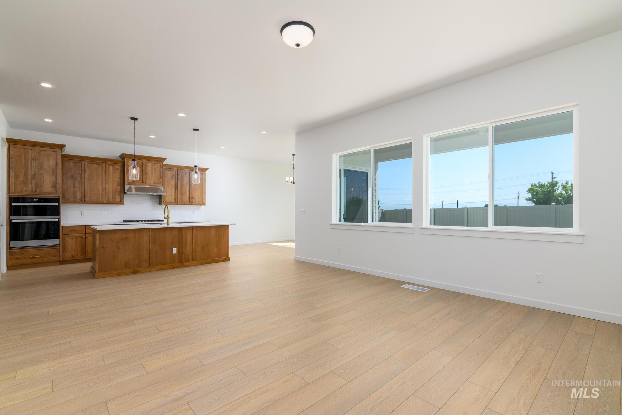Kitchen featuring brown cabinetry, plenty of natural light, under cabinet range hood, light countertops, and recessed lighting