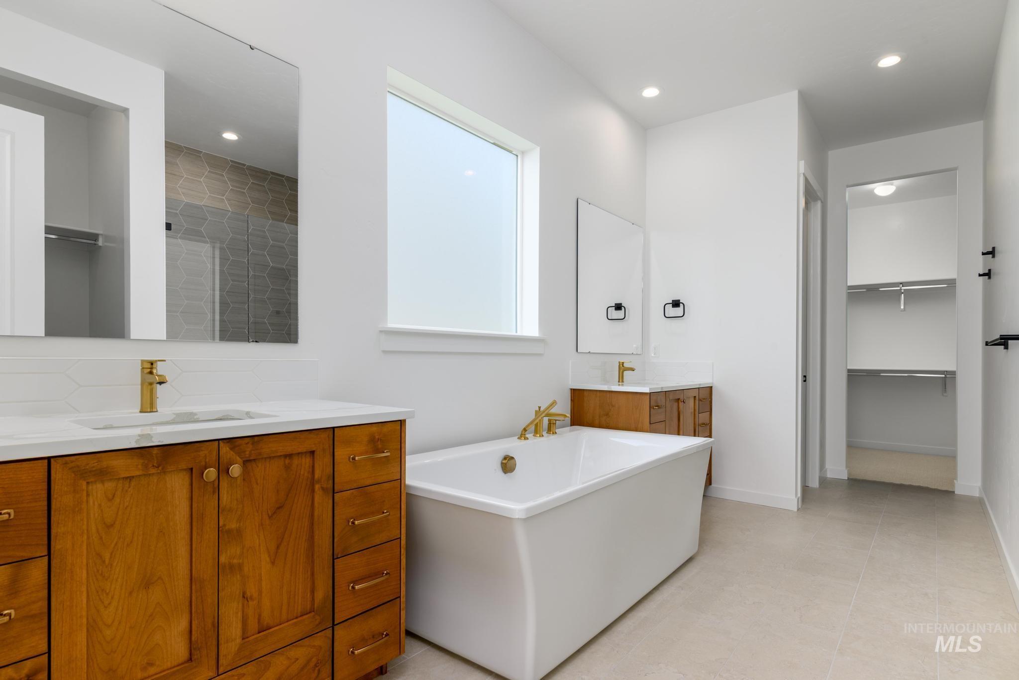 Bathroom featuring vanity, a freestanding bath, backsplash, a spacious closet, and recessed lighting