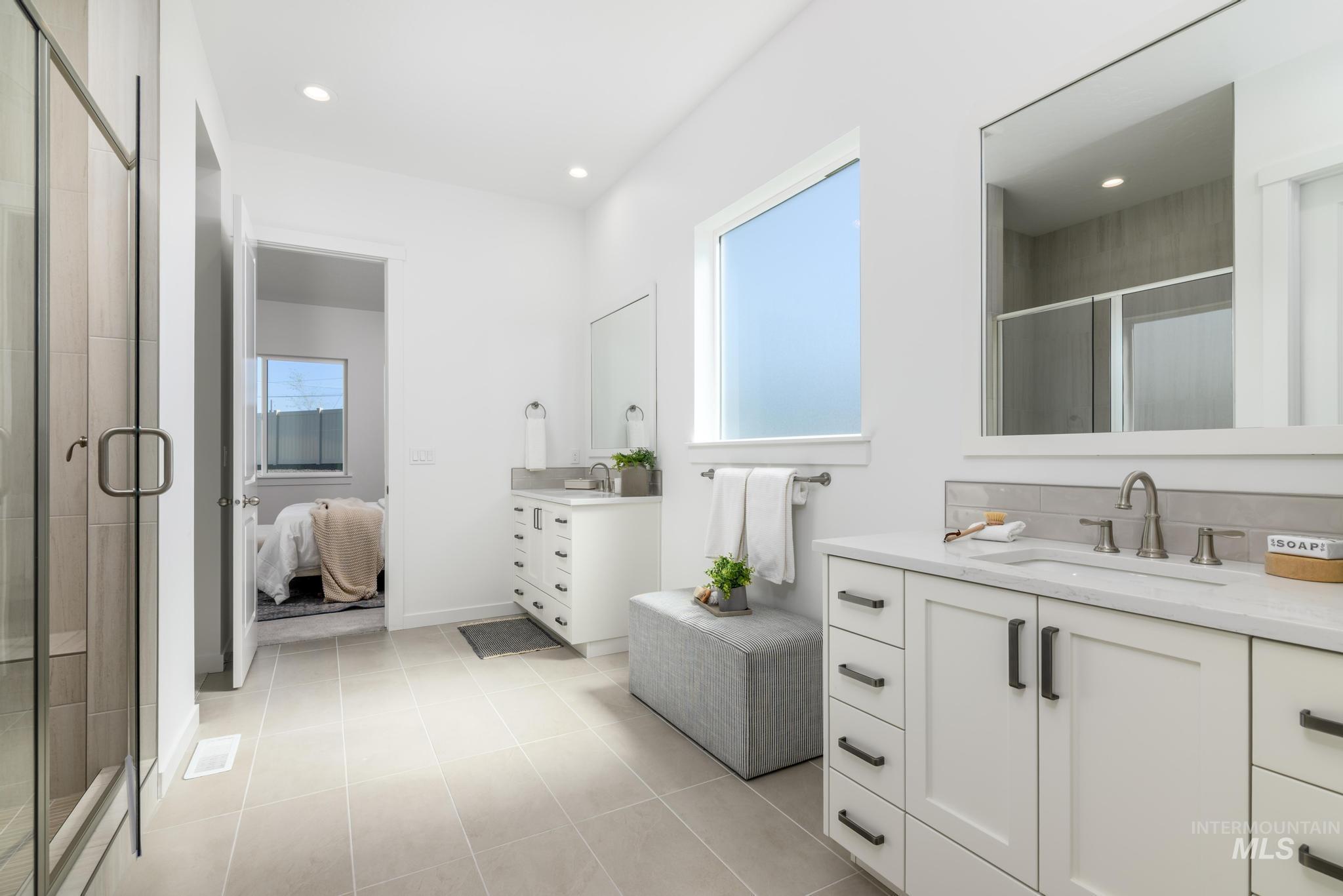 Bathroom with healthy amount of natural light, two vanities, a stall shower, and recessed lighting