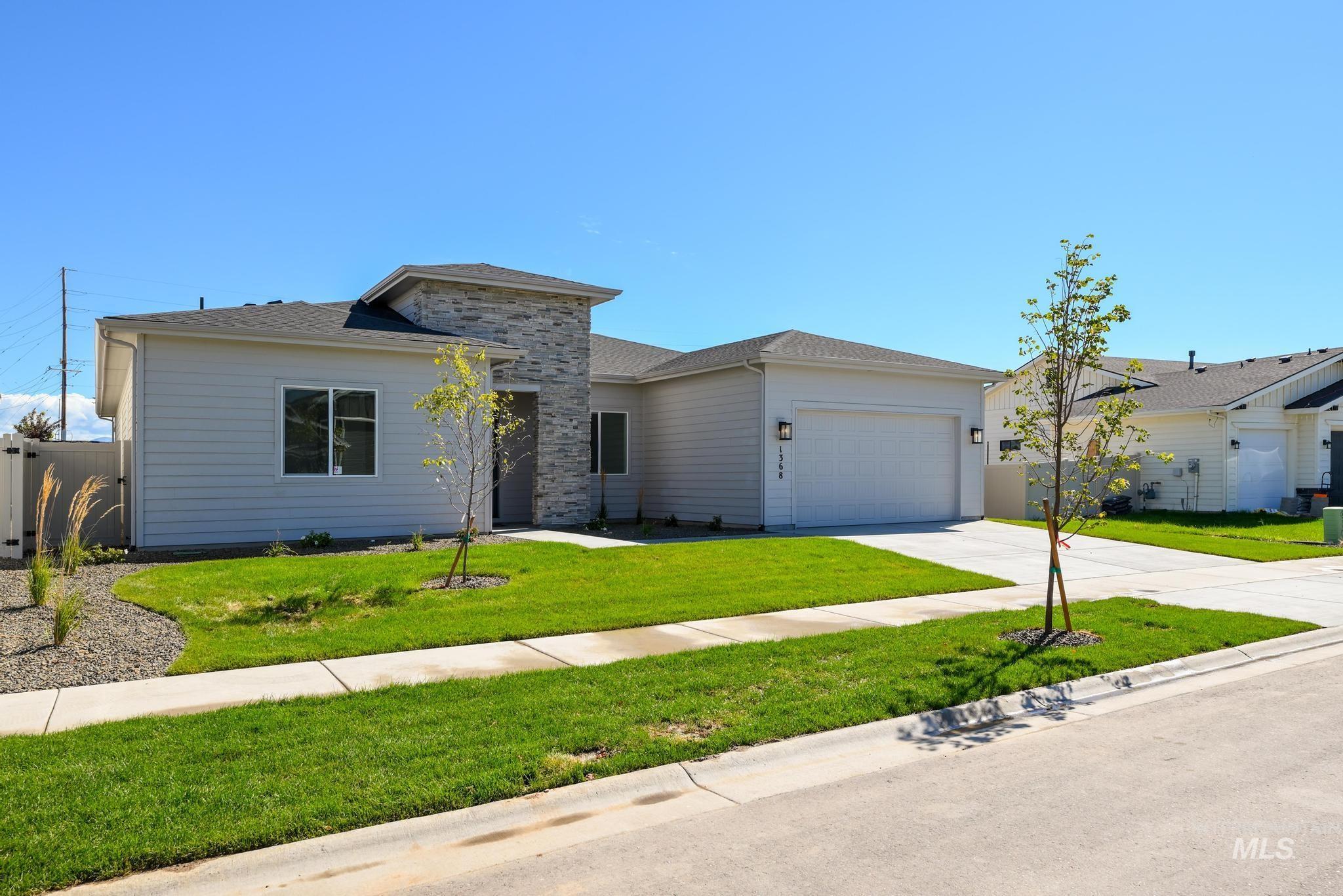 Prairie-style home featuring concrete driveway, an attached garage, a front yard, and a shingled roof