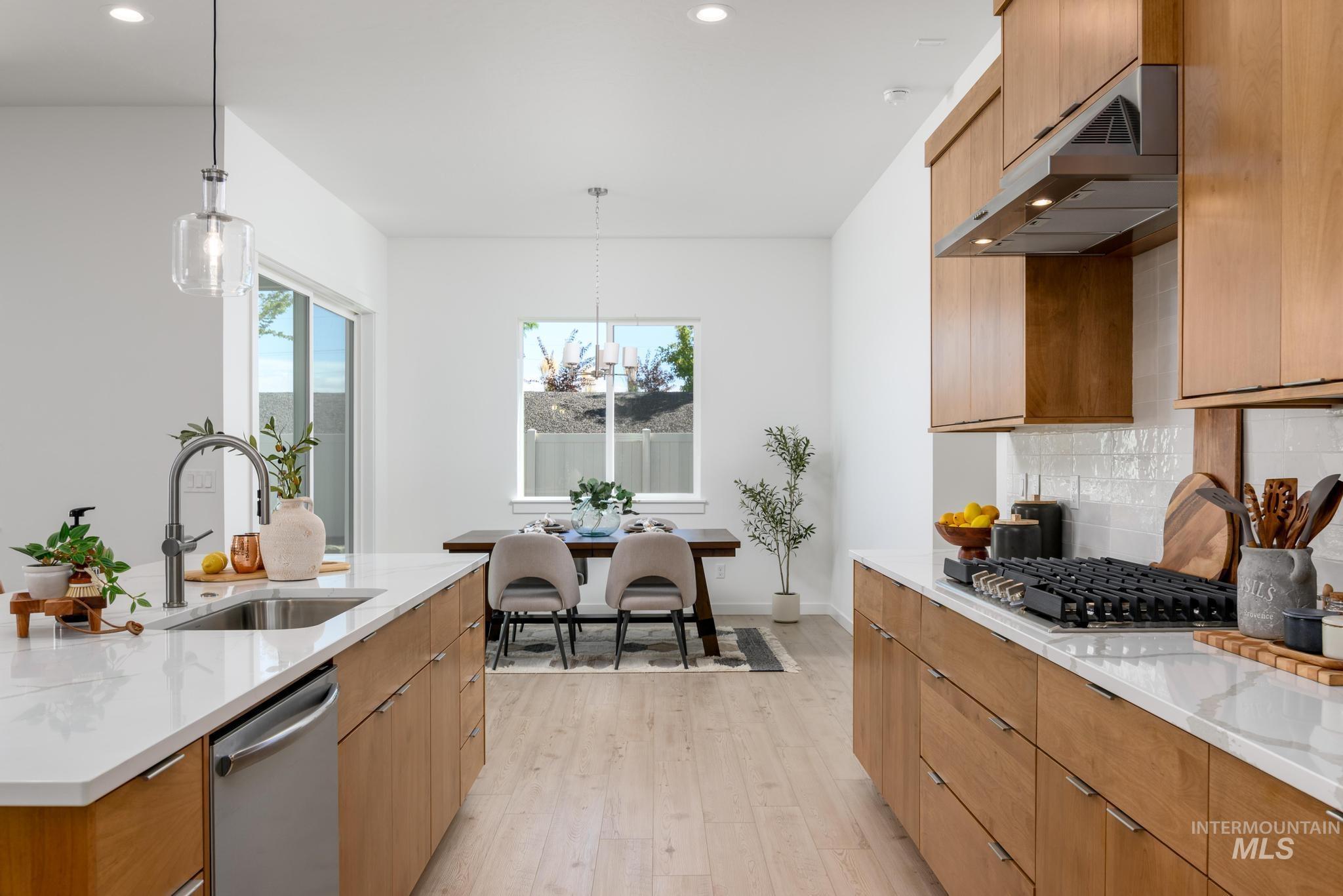 Kitchen with light stone counters, pendant lighting, light wood-style floors, decorative backsplash, and recessed lighting