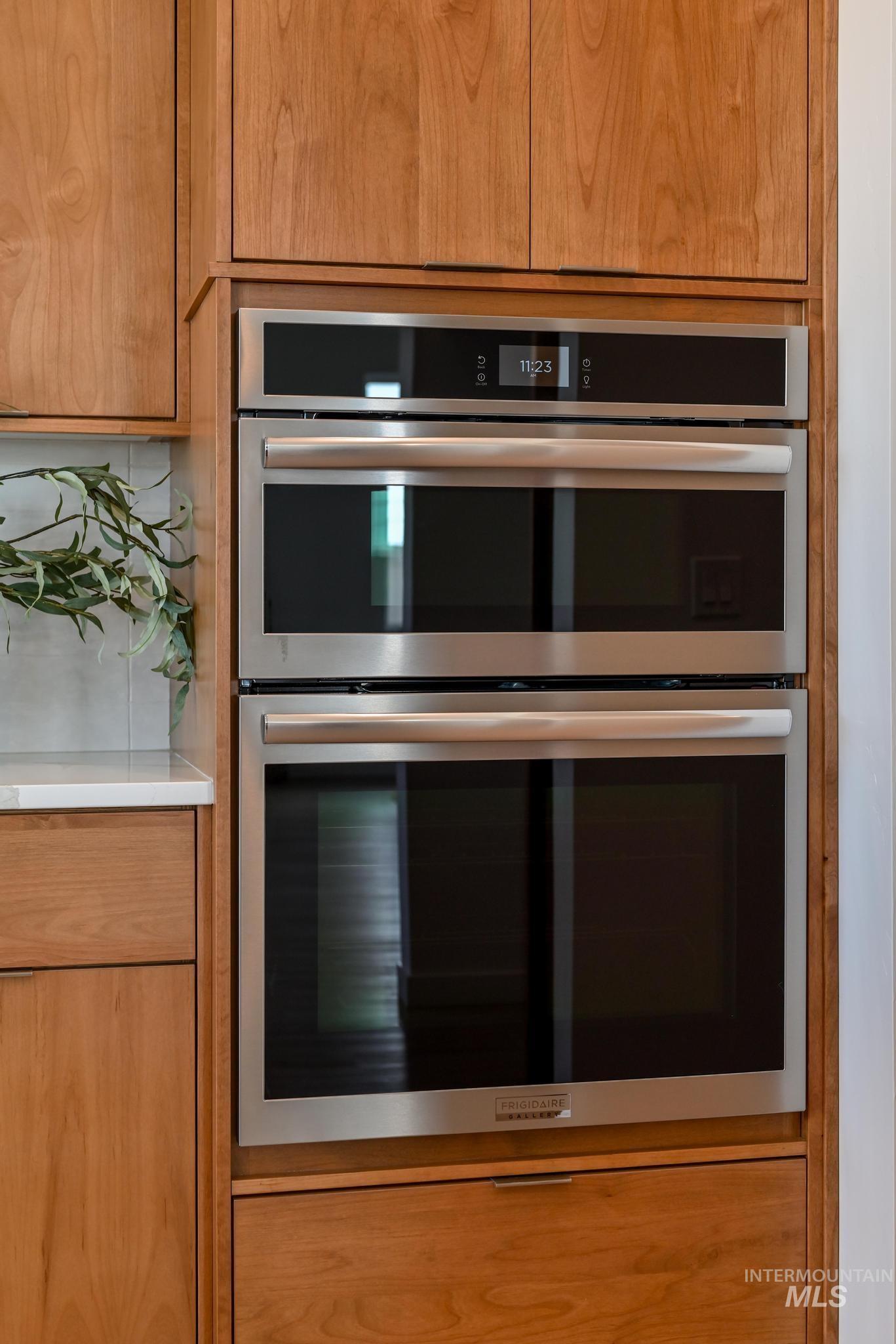 Kitchen featuring stainless steel double oven, brown cabinets, and light countertops