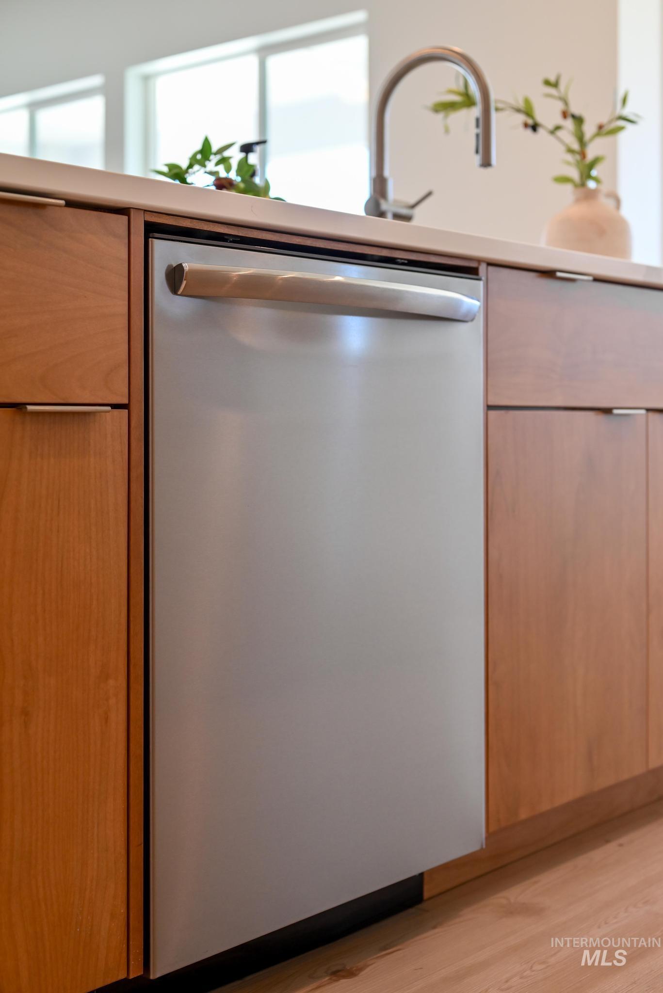 Kitchen view of dishwasher, modern cabinets, light wood-type flooring, and light countertops