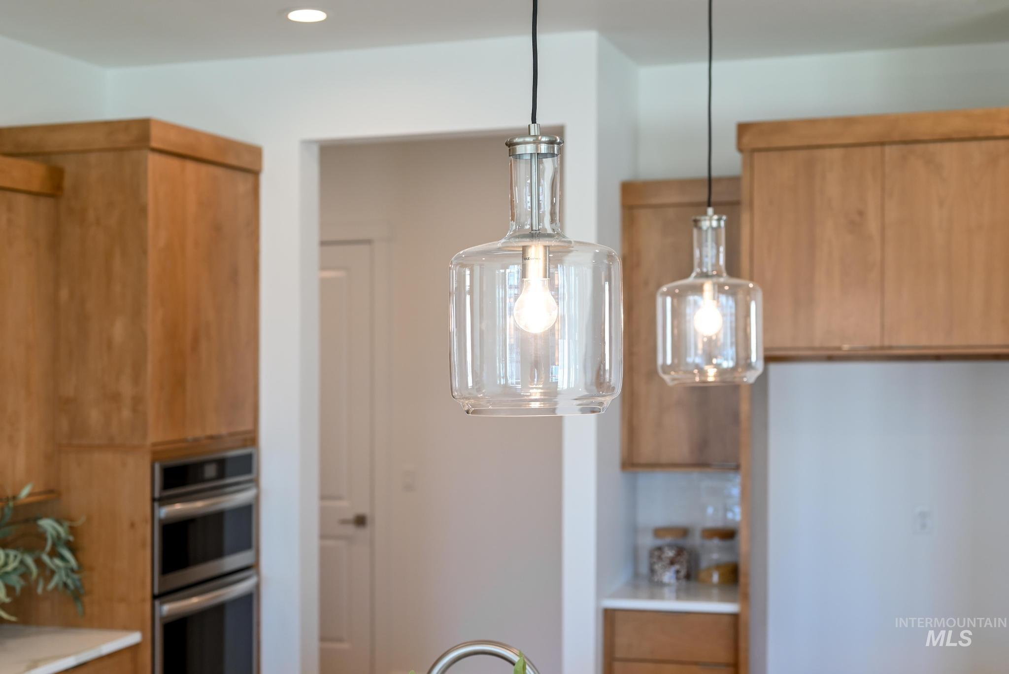 Kitchen featuring decorative light fixtures, brown cabinetry, double oven, modern cabinets, and recessed lighting
