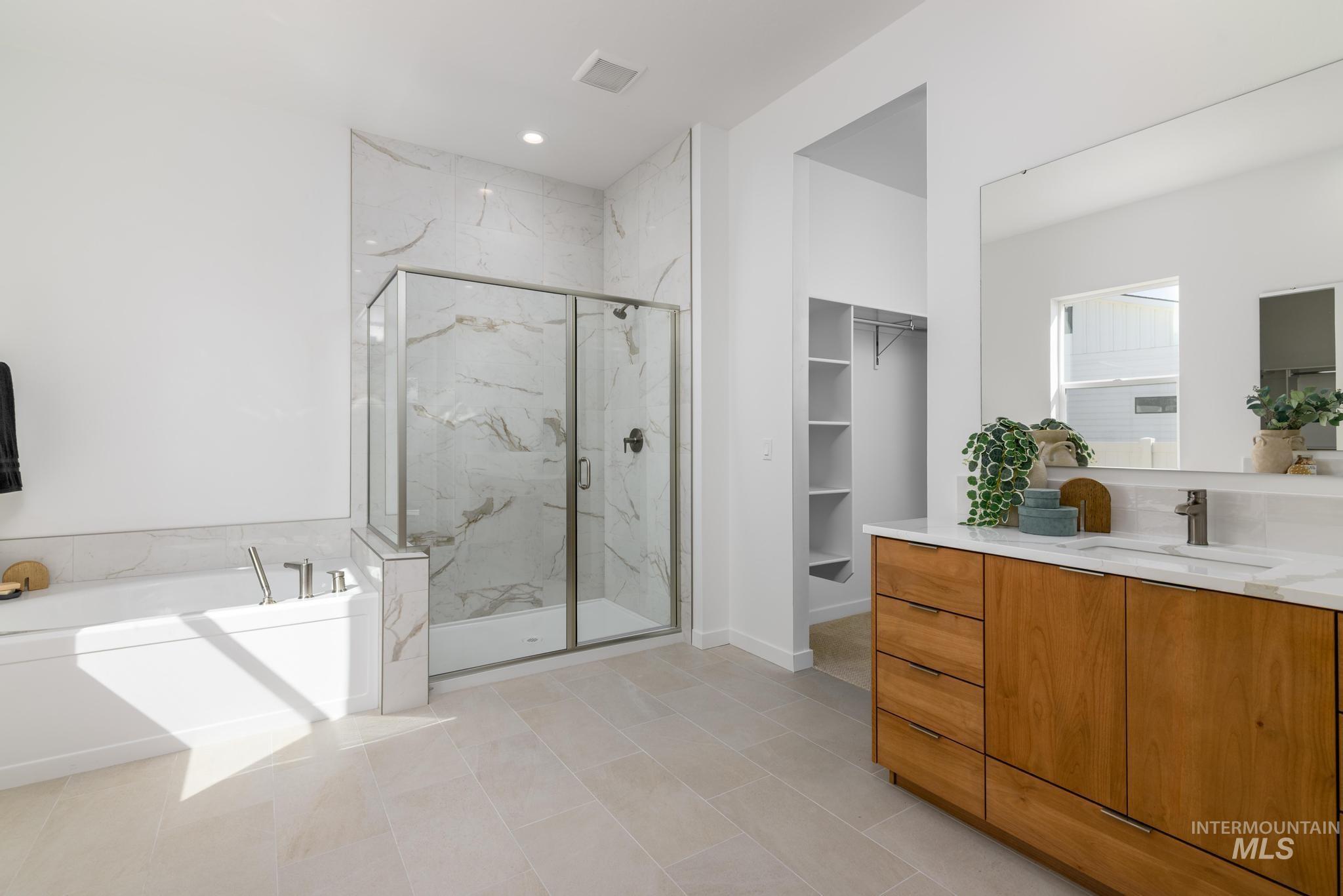 Bathroom featuring a bath, a marble finish shower, vanity, light tile patterned flooring, and recessed lighting