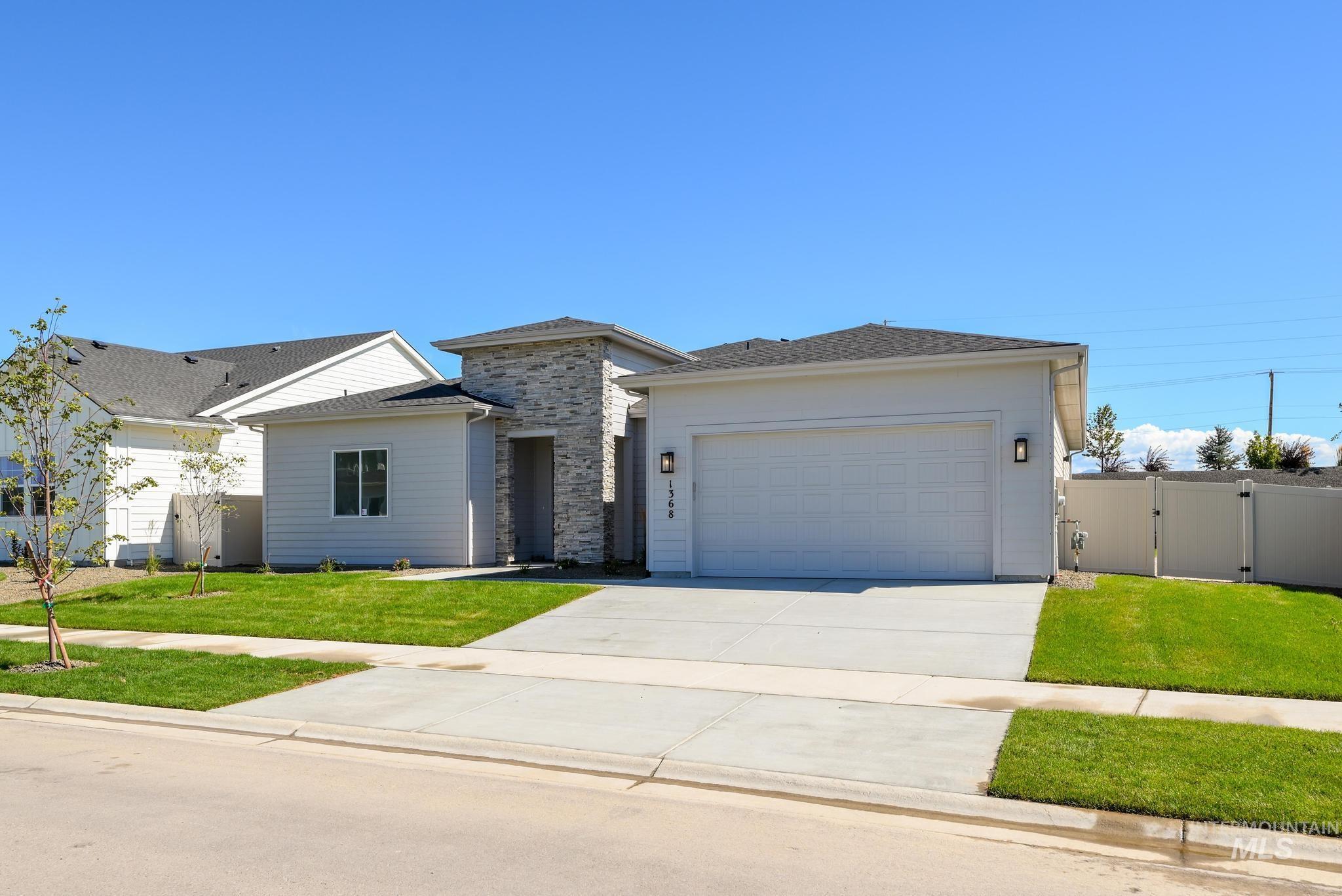 Prairie-style home with a gate, driveway, a garage, and stone siding