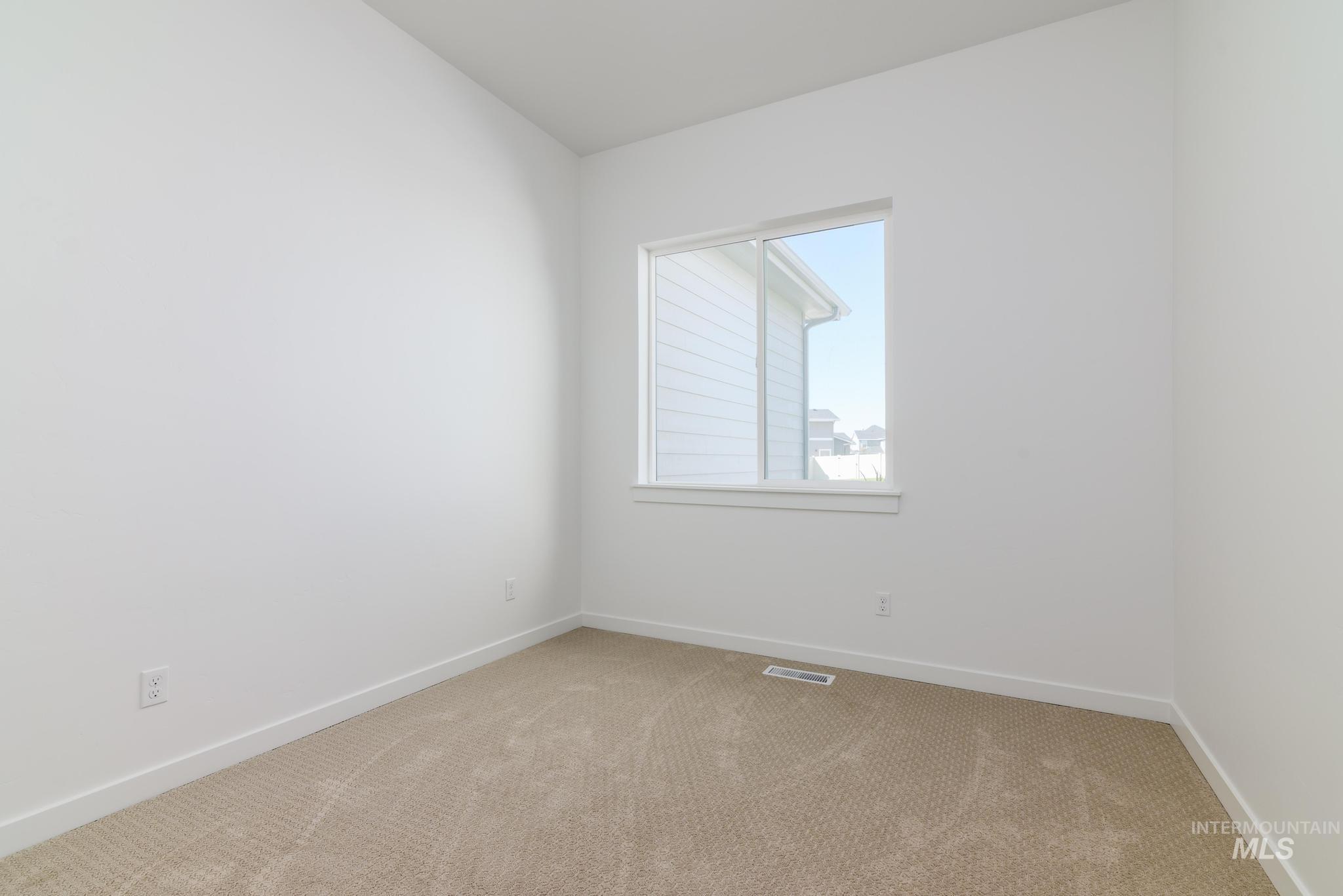 Carpeted spare room featuring baseboards