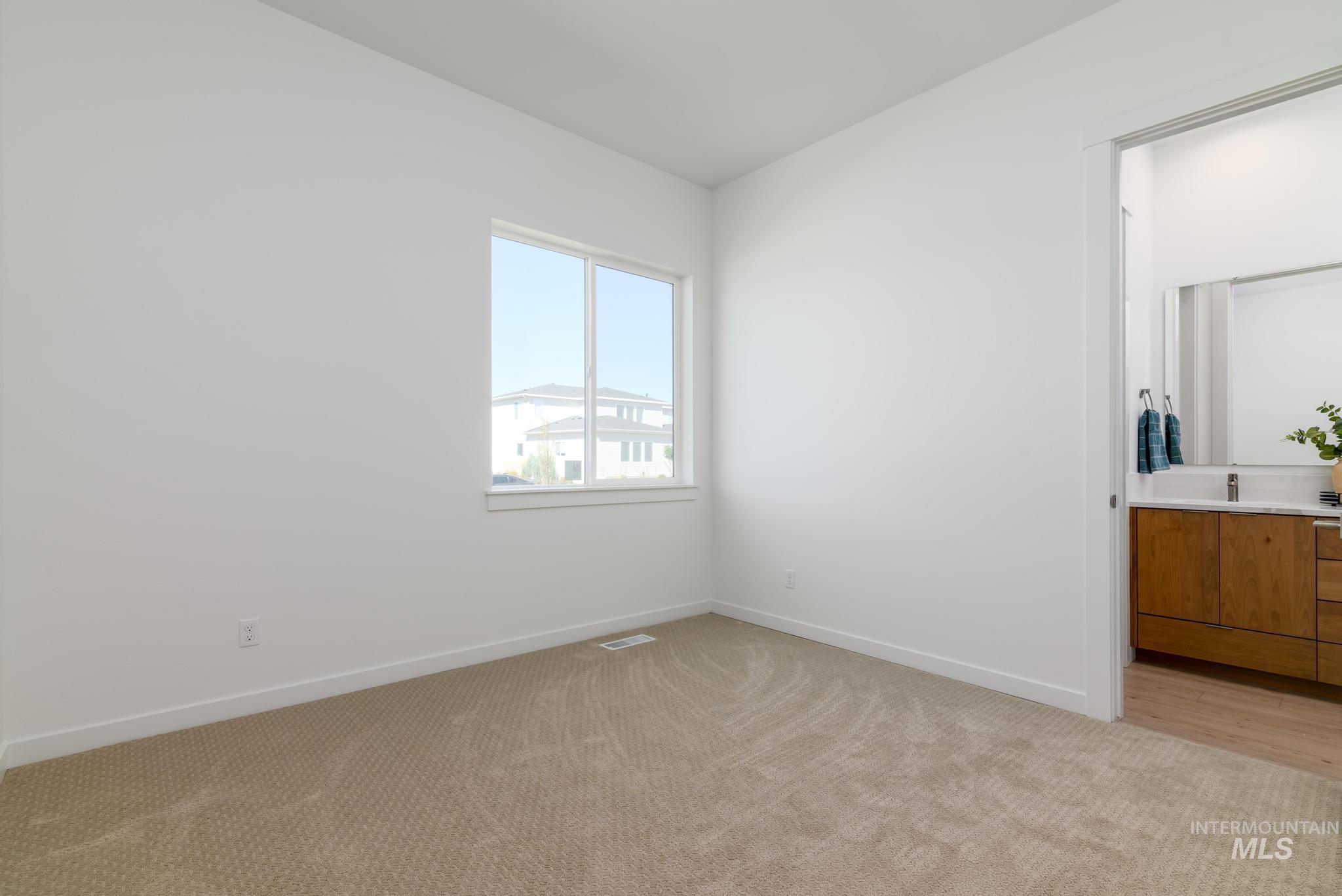Unfurnished bedroom with light carpet and baseboards