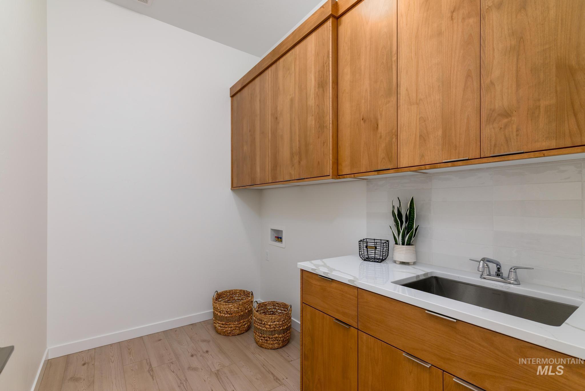 Laundry area with light wood-style flooring, hookup for a washing machine, and cabinet space