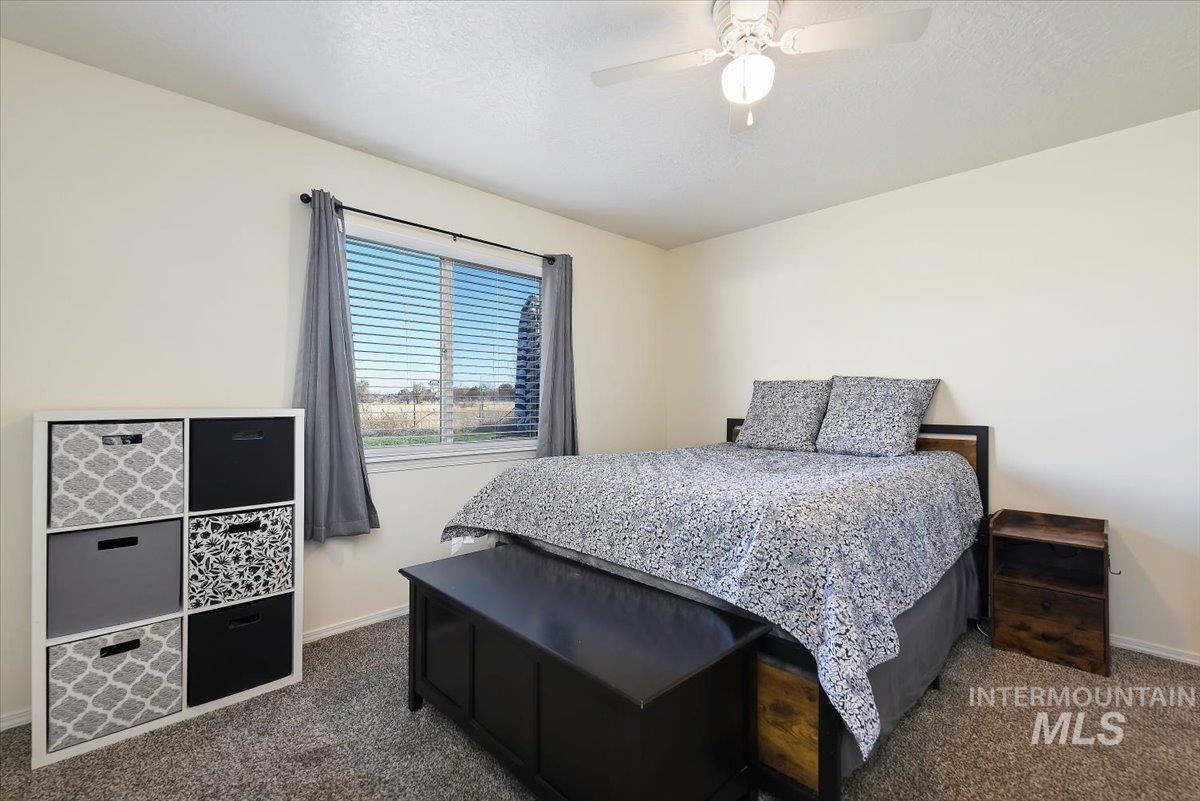 Bedroom featuring a ceiling fan, dark colored carpet, and a textured ceiling
