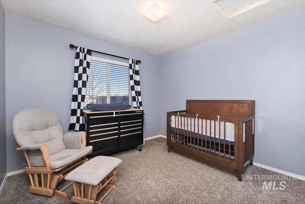 Bedroom with a crib, a textured ceiling, and carpet flooring
