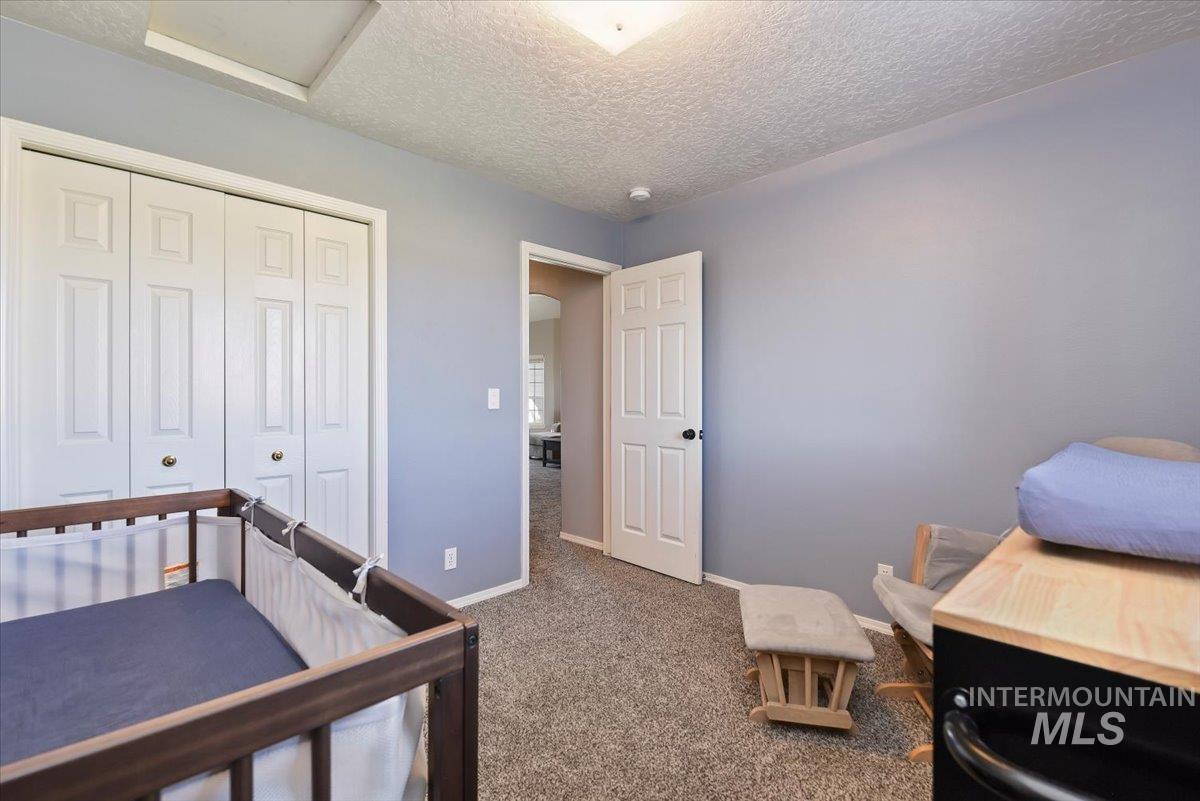 Bedroom with a textured ceiling, carpet flooring, and a closet