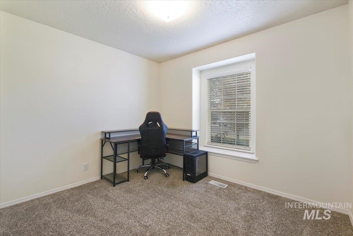 Carpeted home office featuring baseboards and a textured ceiling