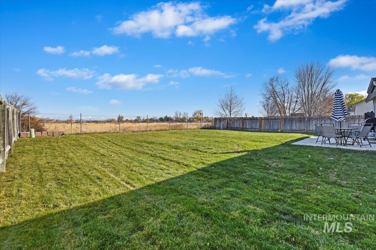 Fenced backyard with a patio and a view of countryside