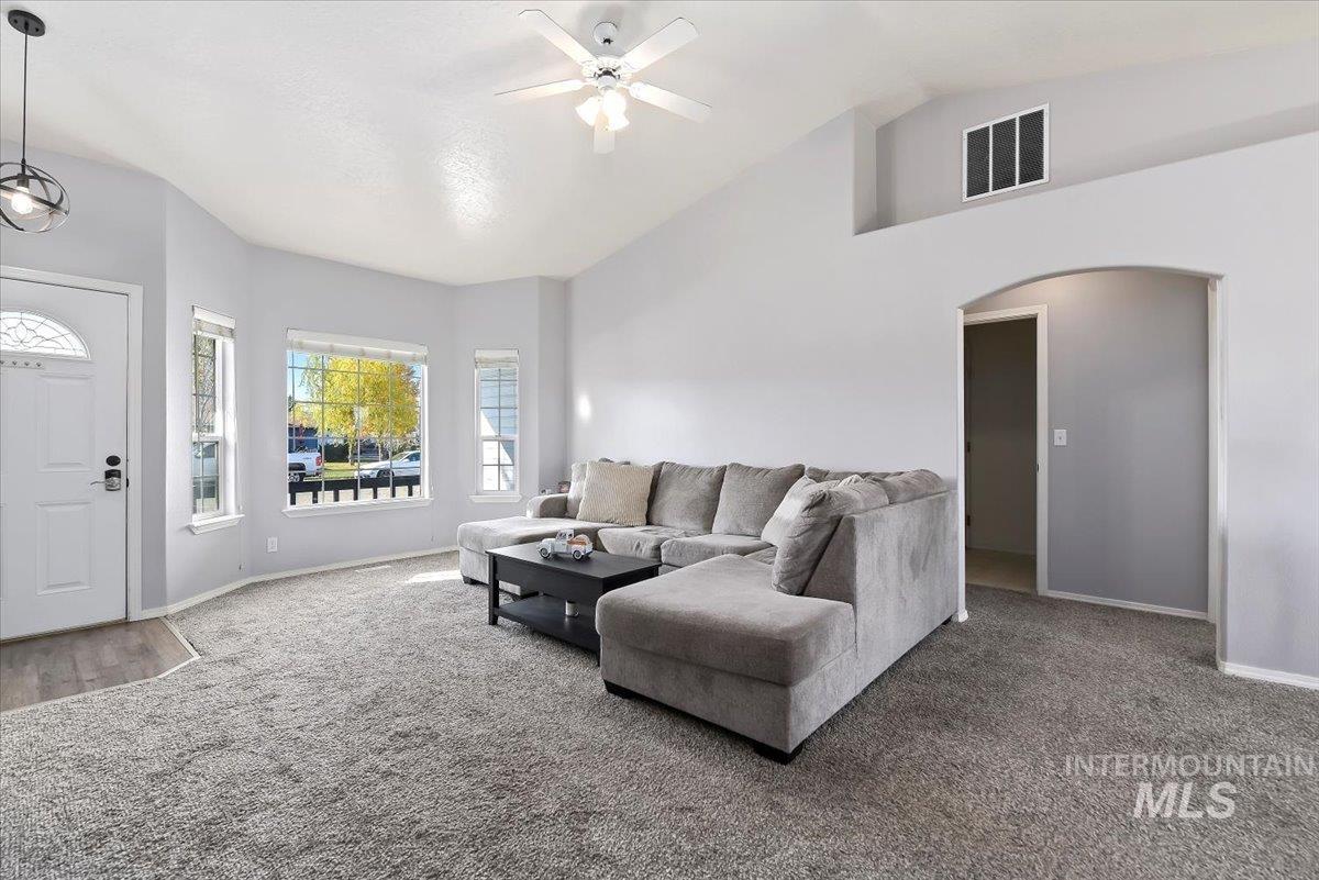 Living room featuring carpet floors, arched walkways, high vaulted ceiling, and ceiling fan