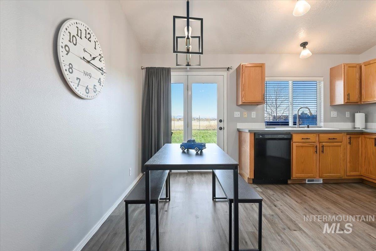 Kitchen featuring light wood finished floors, black dishwasher, light countertops, decorative light fixtures, and a textured ceiling