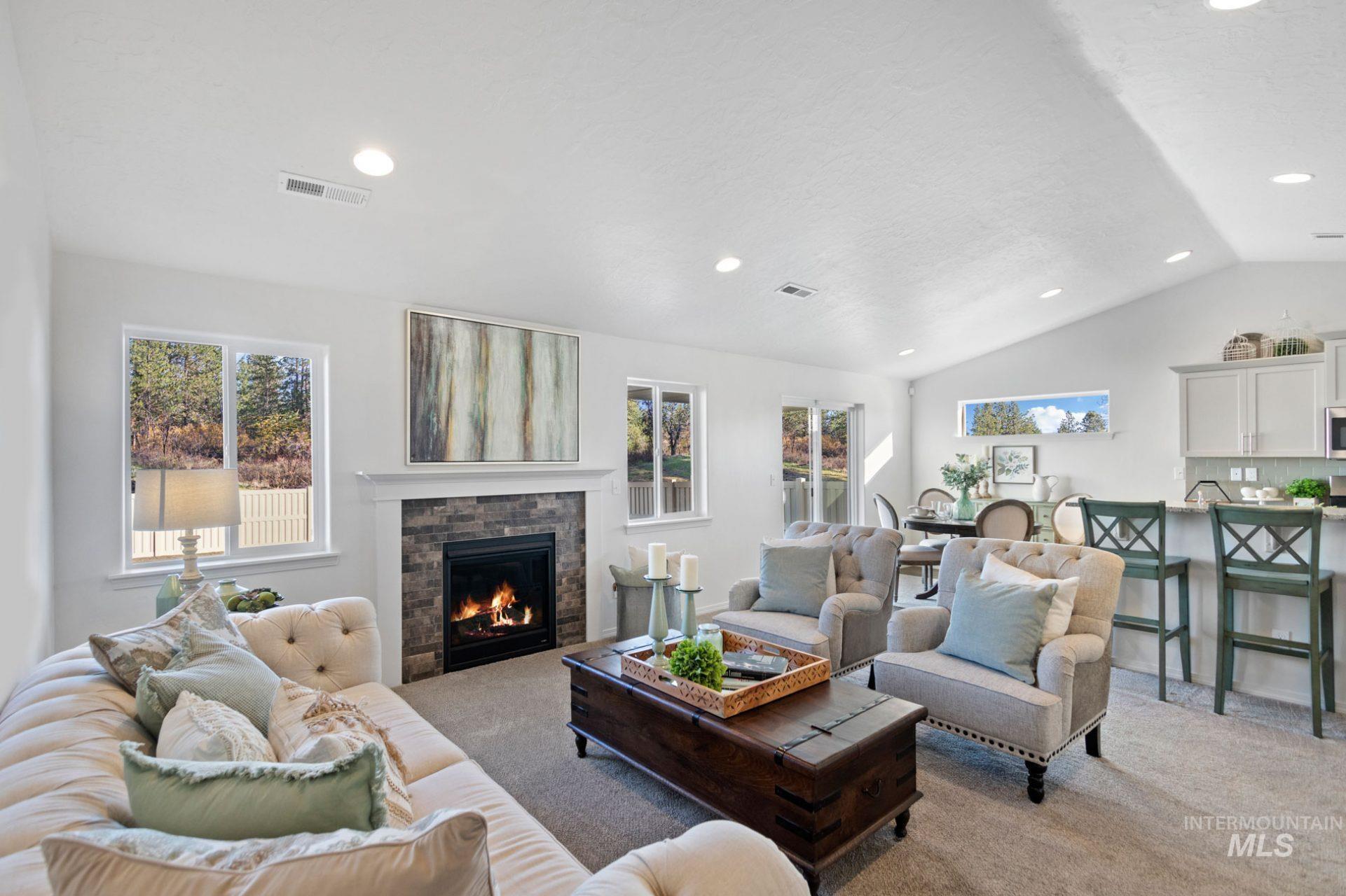 Living room with plenty of natural light, recessed lighting, light carpet, a warm lit fireplace, and vaulted ceiling