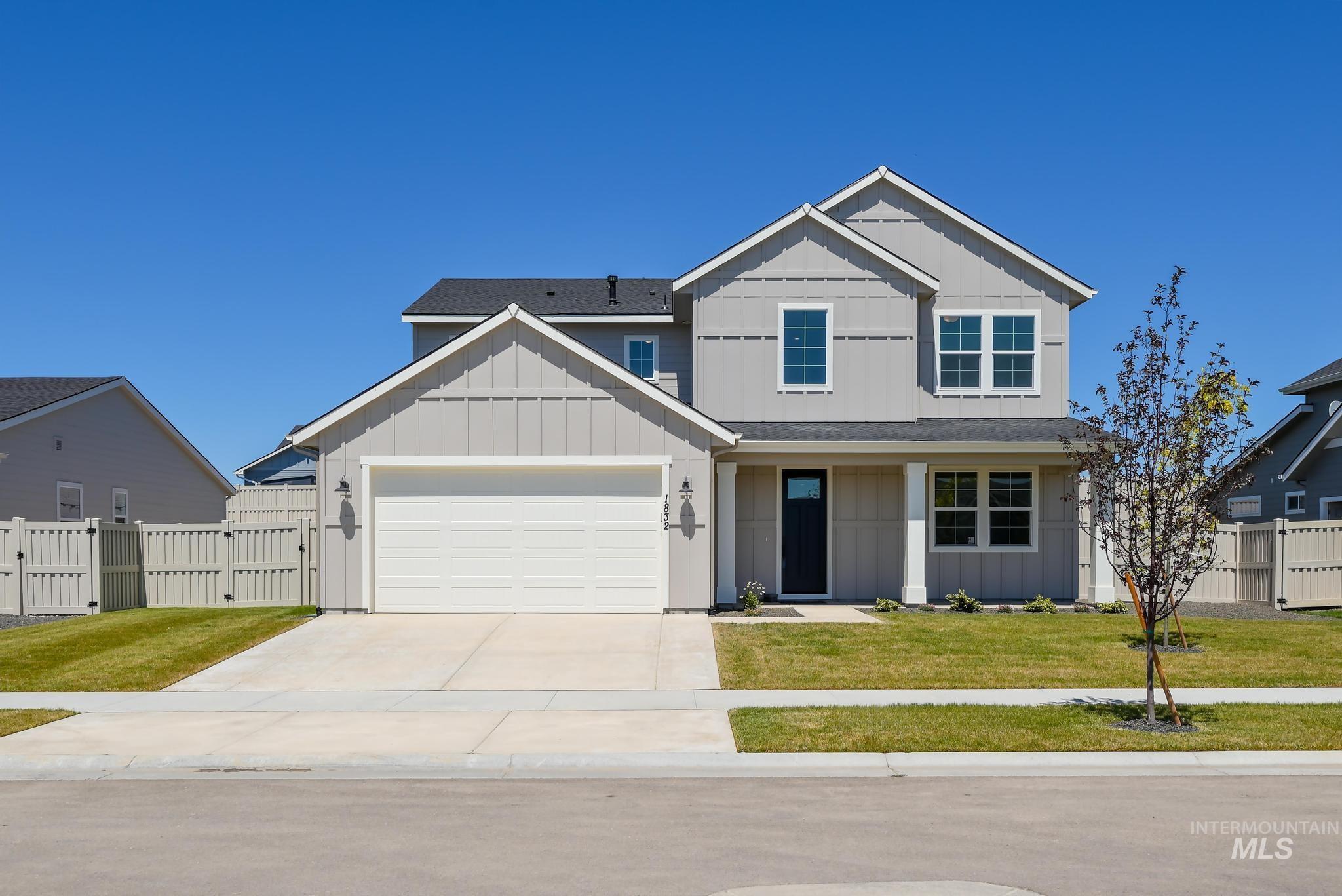View of front facade with board and batten siding, a gate, and driveway