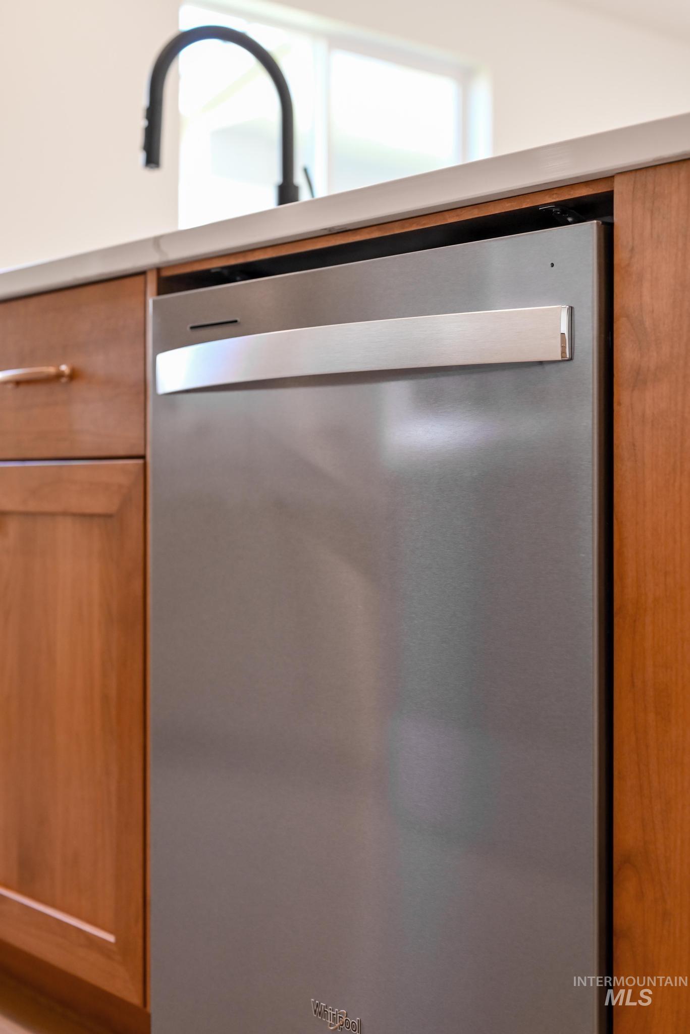 Kitchen view of stainless steel dishwasher and brown cabinetry