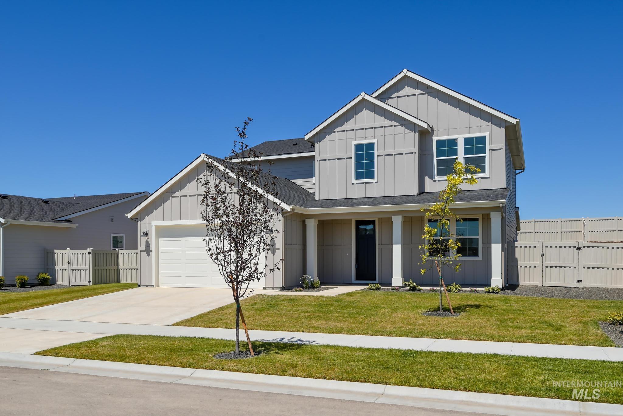 View of front of house featuring board and batten siding, a gate, an attached garage, and concrete driveway