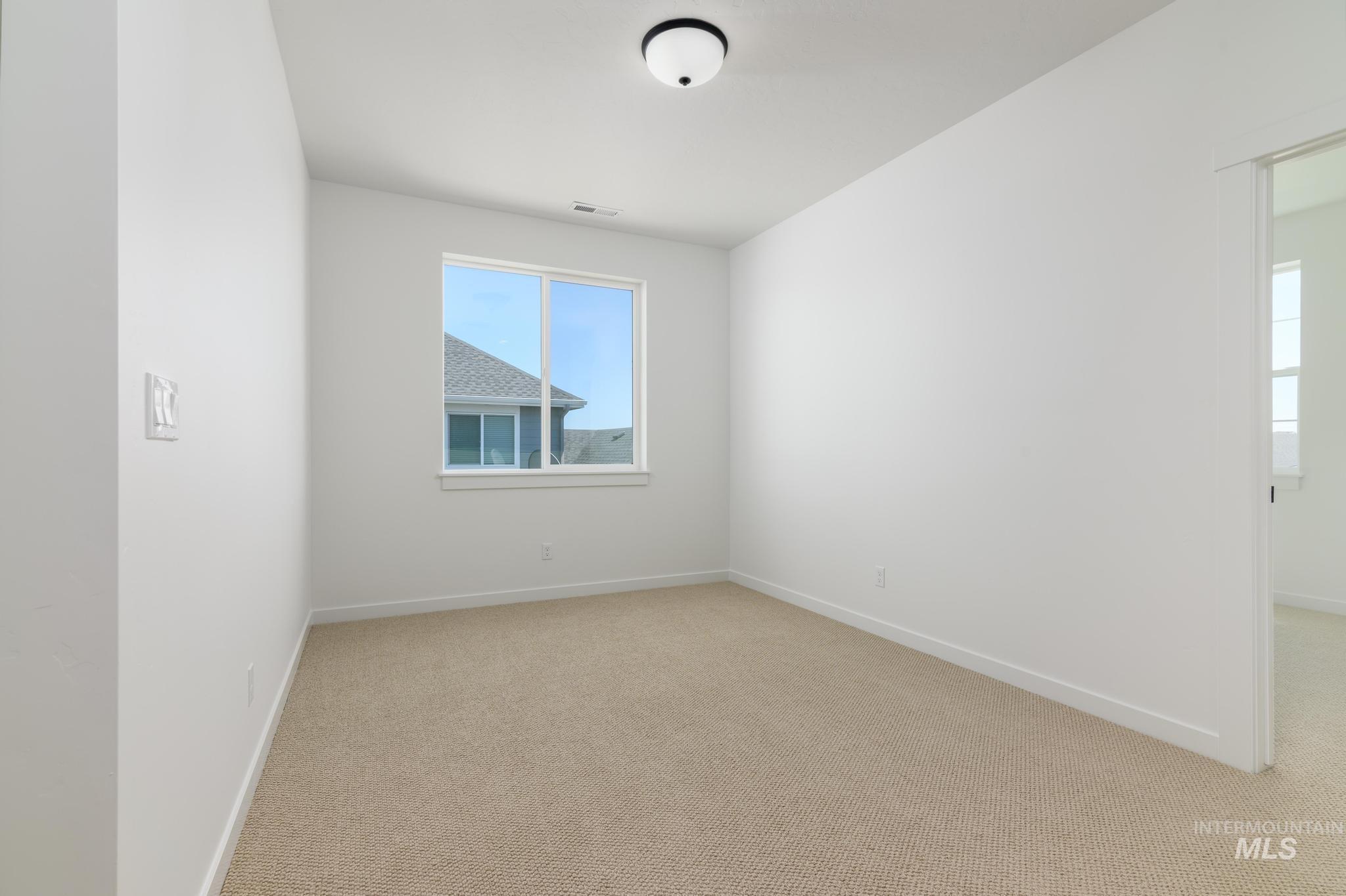 Spare room featuring light colored carpet and baseboards
