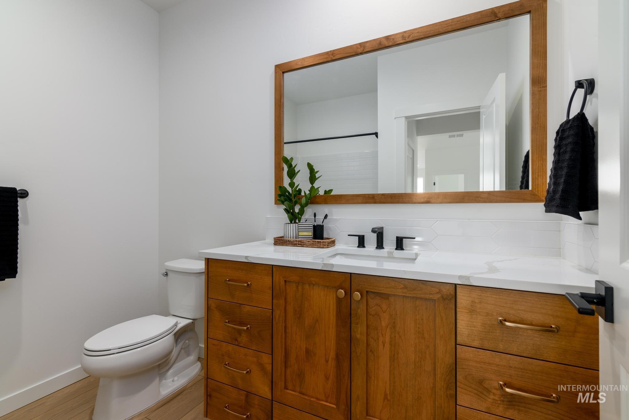 Bathroom featuring vanity, backsplash, and light wood-style flooring
