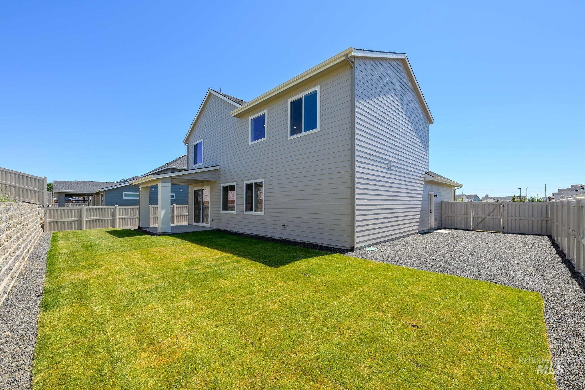 Back of house with a fenced backyard, a patio, and a gate