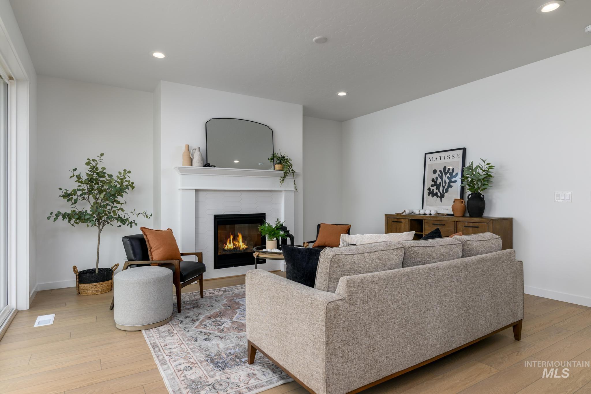 Living area with recessed lighting, a brick fireplace, and light wood-style floors