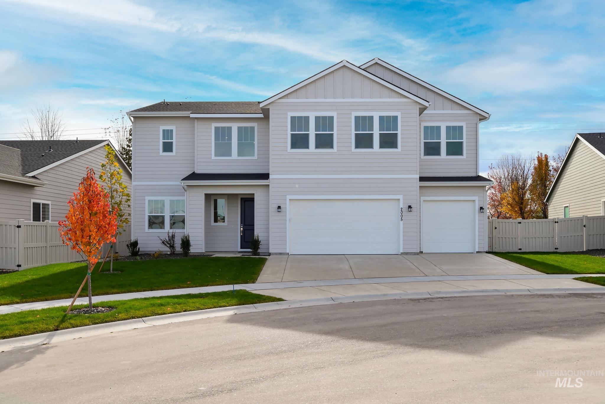 View of front facade featuring board and batten siding, driveway, an attached garage, and a gate