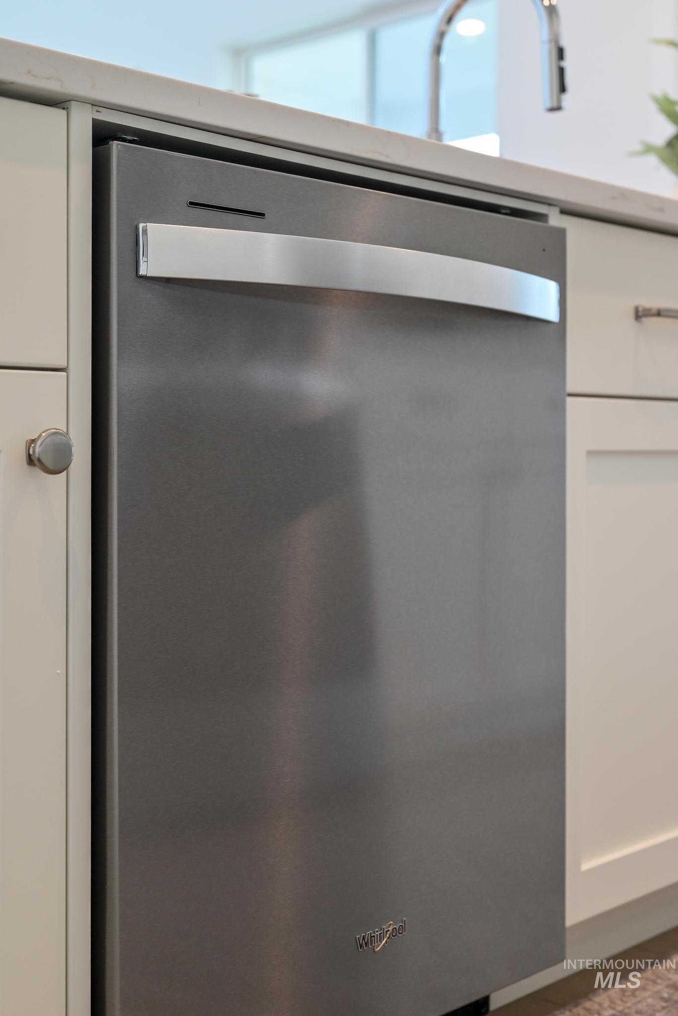 Kitchen view of dishwasher and white cabinets