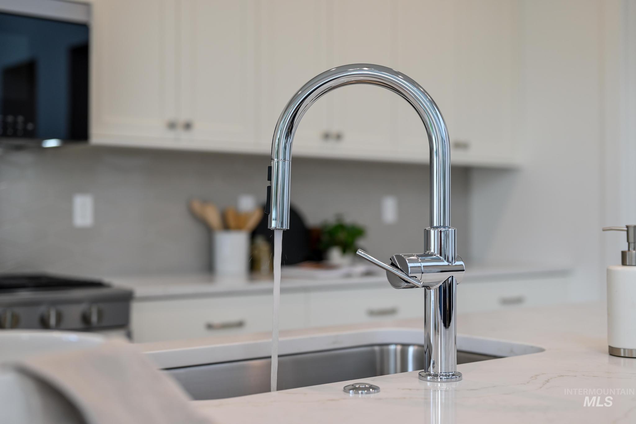 Kitchen view of white cabinets, stainless steel stove, and light stone counters